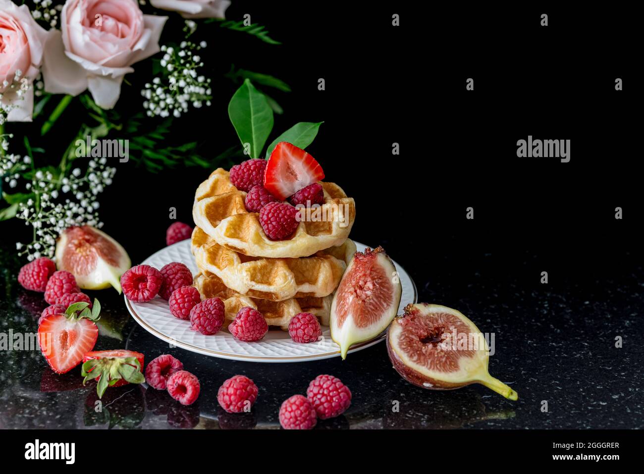 Impila di waffle con lamponi, fragole e fichi. La colazione era squisita. Foto Stock
