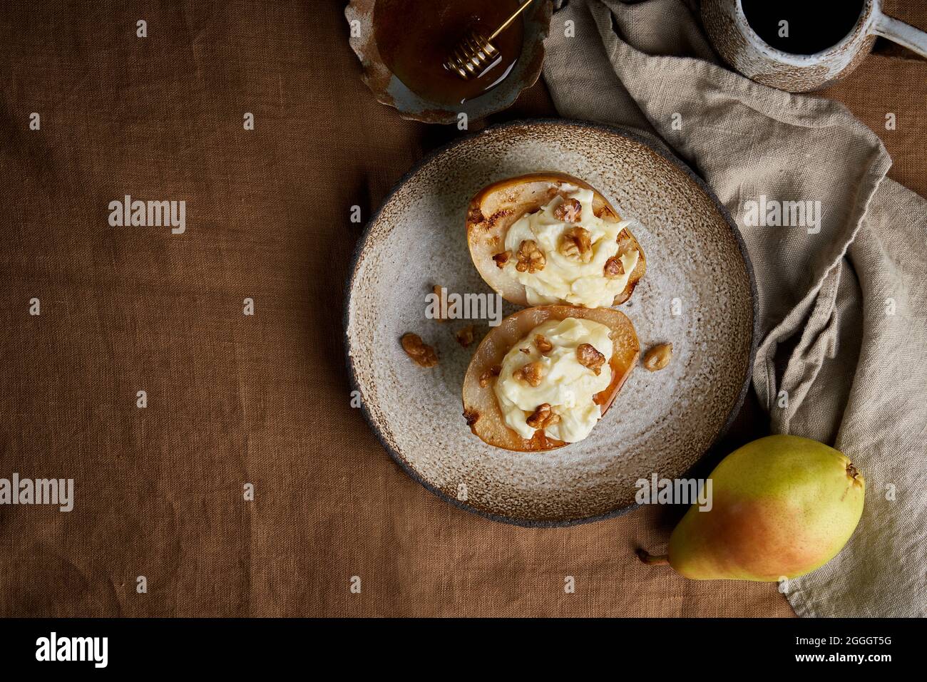 Pere dolci alla griglia con noci e miele. Servito su tovaglia marrone dessert autunnale Foto Stock