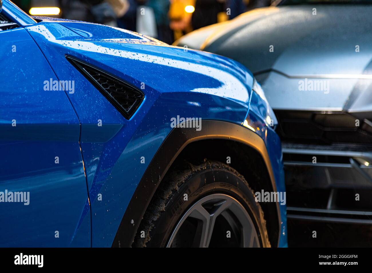 Due auto blu e grigio vogliono prendere un posto auto. Problemi di parcheggio in città. Parcheggiato strettamente l'uno all'altro. Paraurti strappato. Auto basse sintonizzate wit Foto Stock