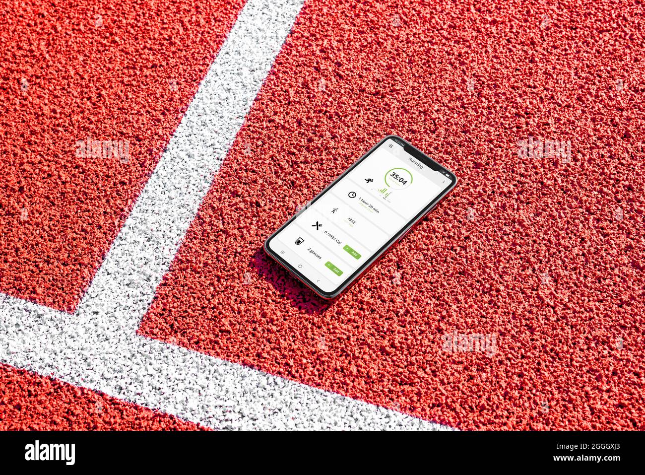 Telefono con concetto di app running sul campo di atletica. Statistiche su tempo, distanza e calorie Foto Stock