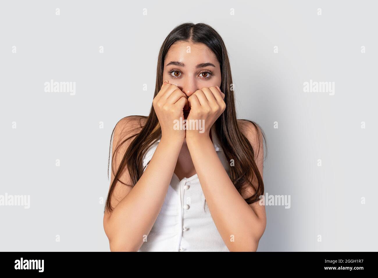 giovane femmina, spaventato e stressato ha messo le mani in bocca e spalancato gli occhi. Foto di alta qualità Foto Stock