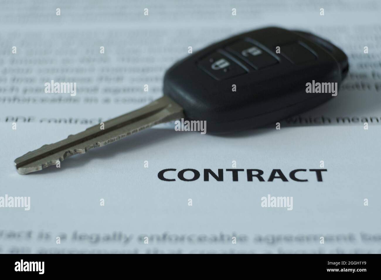 C'è un contratto e le chiavi di automobile sul tavolo, l'enfasi è sul nome del documento e le chiavi. Immagine sfocata. Foto Stock