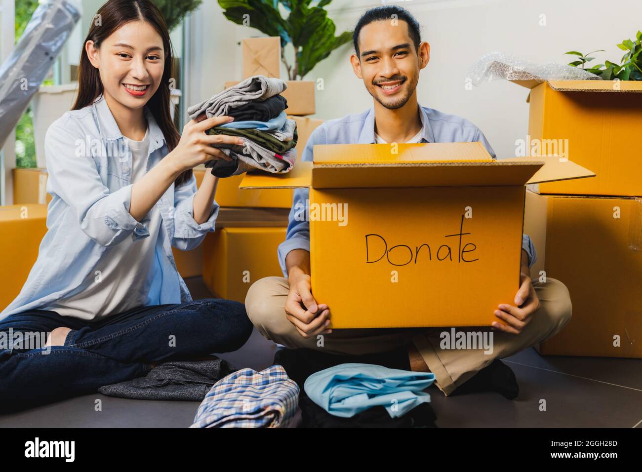 L'uomo volontario asiatico e la donna imballaggio scatola di stoffa e donare ad altre persone e condividere la carità Foto Stock