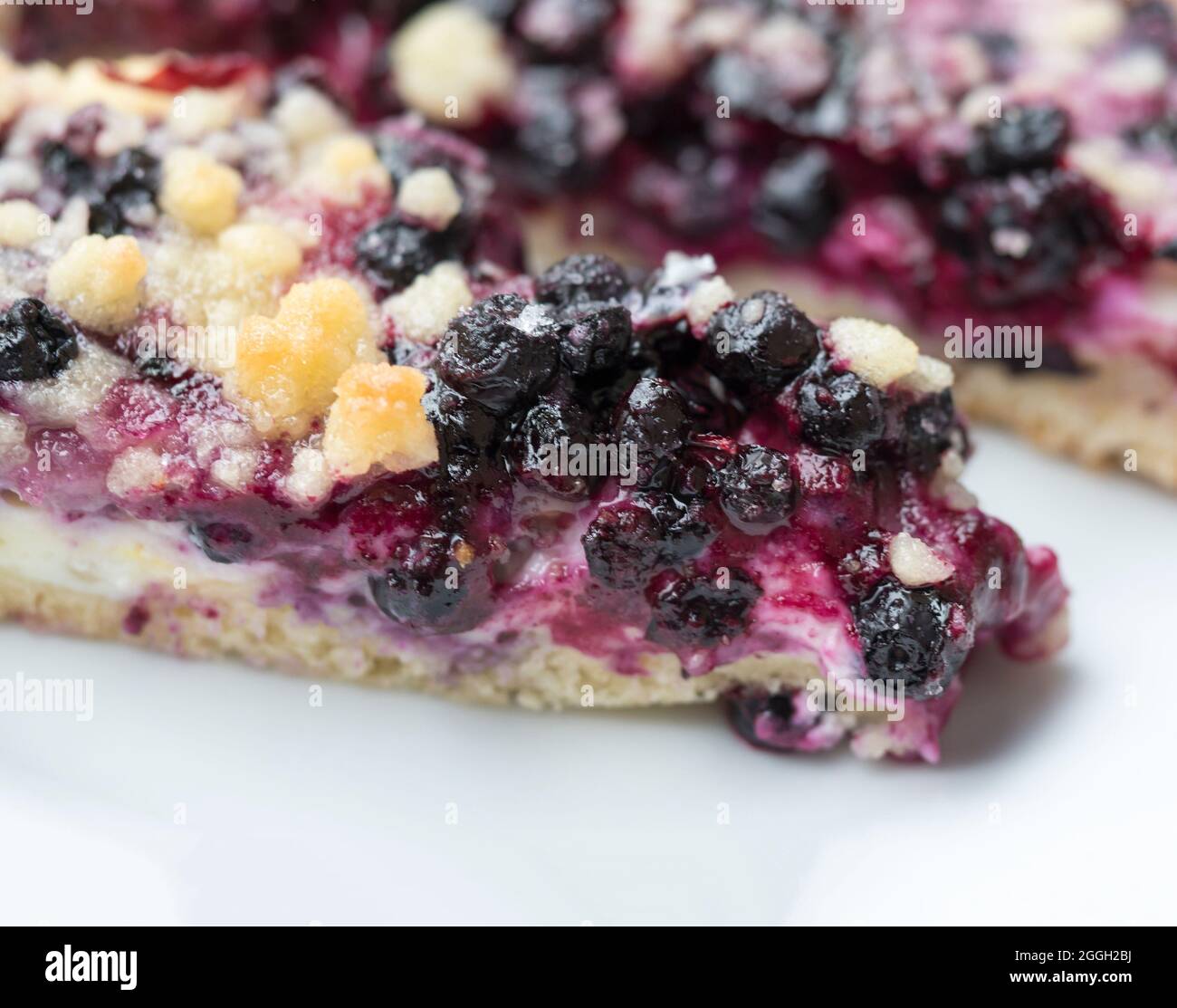 pezzi di torta al mirtillo fatta in casa con formaggio casereccio e crumble, il cibo da vicino, macro su sfondo bianco Foto Stock