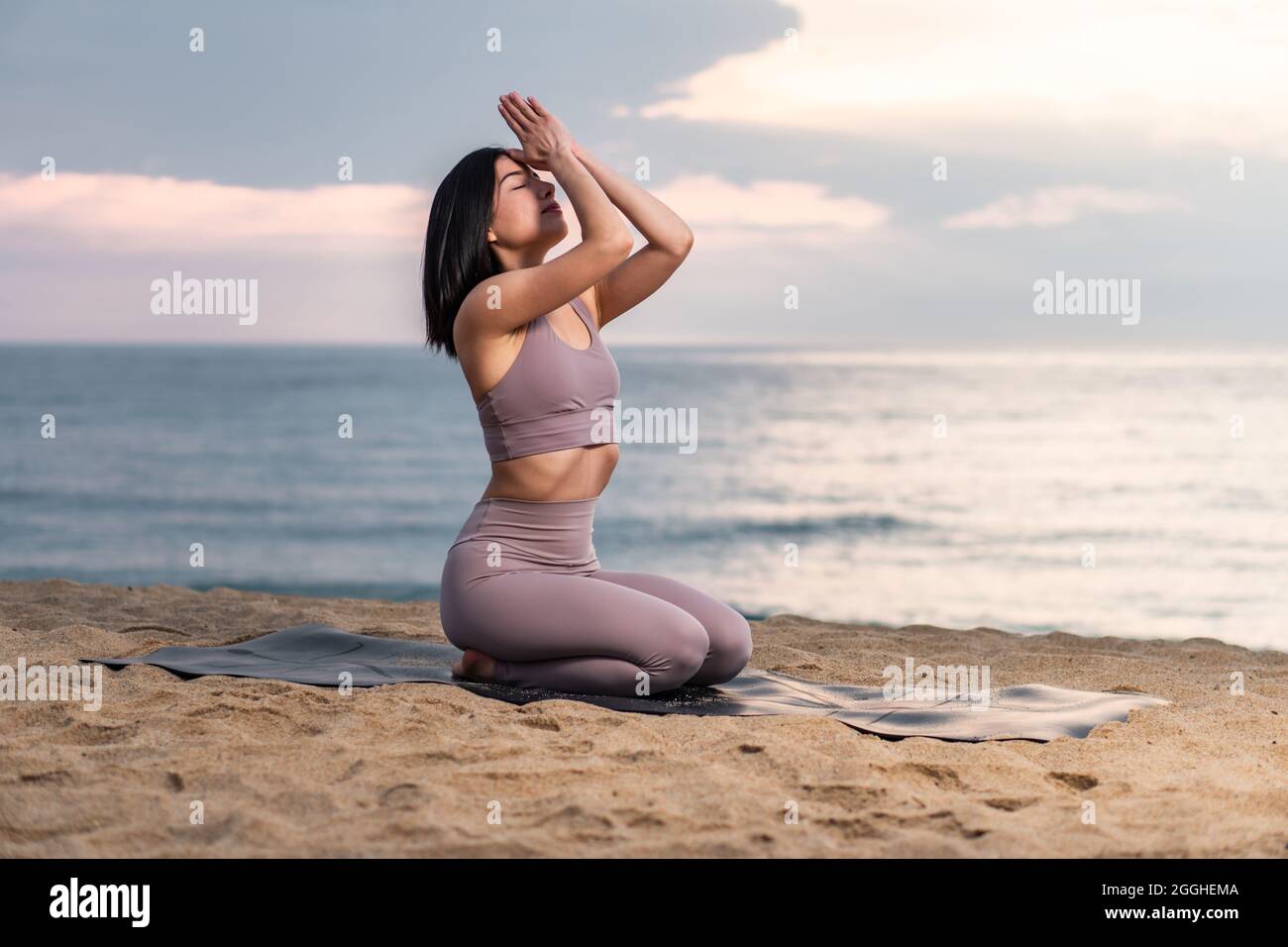 Giovane donna che pratica yoga in spiaggia all'alba. Stile di vita sano. Esercizio di mente e corpo Foto Stock