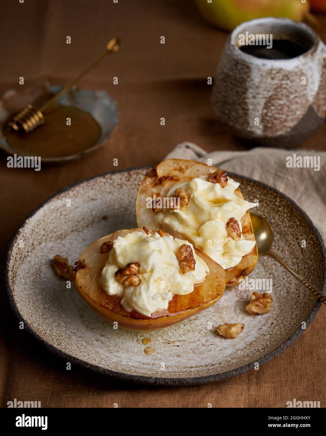 Dolce dessert rustico. Pere arrosto con panna e noci su sfondo di legno. Miele e caffè Foto Stock