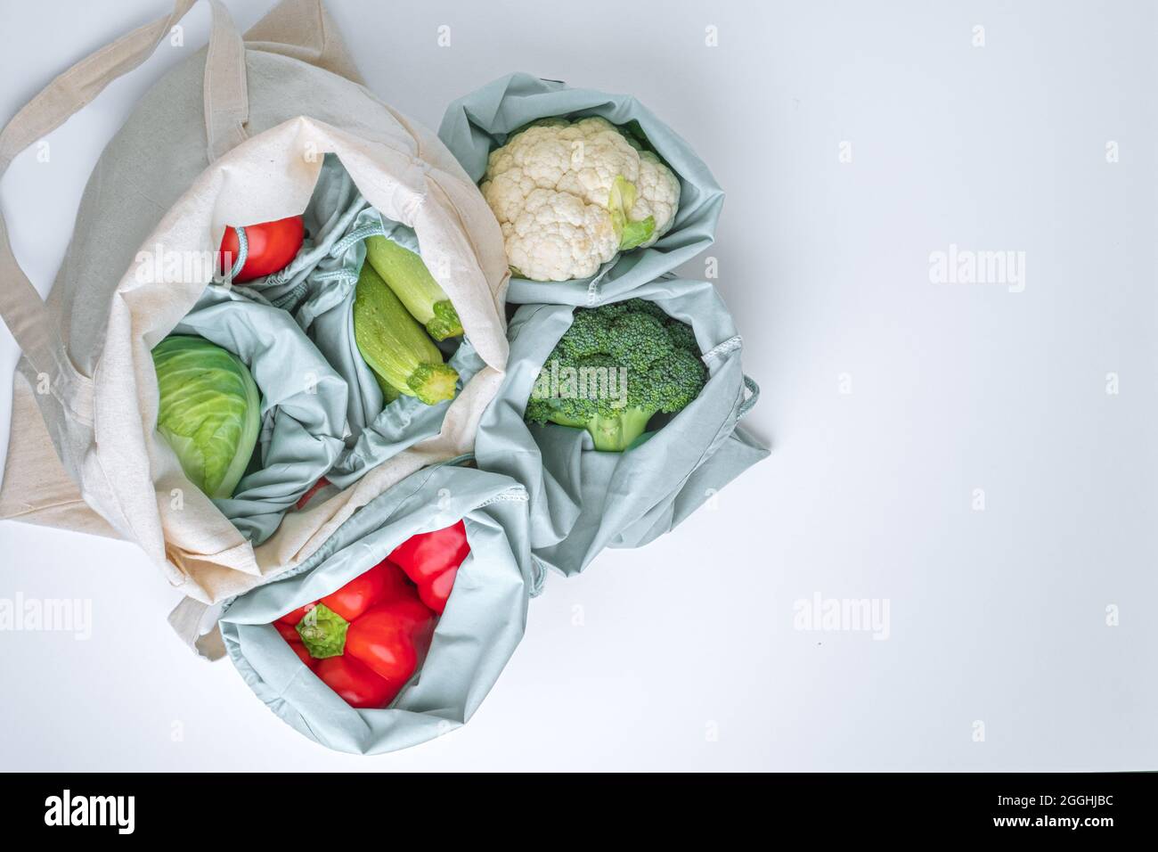 Verdure fresche in borse di spesa tessile su un tavolo bianco, concetto di zero rifiuti. Spazio di disposizione piatta per il testo. Vista dall'alto. . Foto di alta qualità Foto Stock