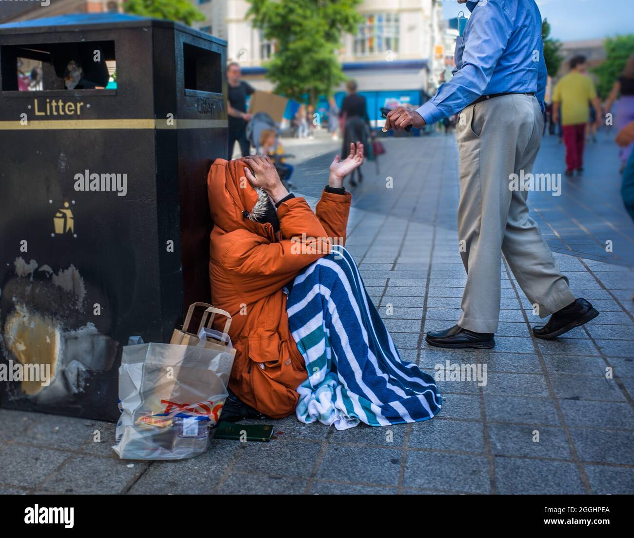 Un uomo dà soldi ad un uomo senza tetto che implora per strada a Liverpool. Foto Stock