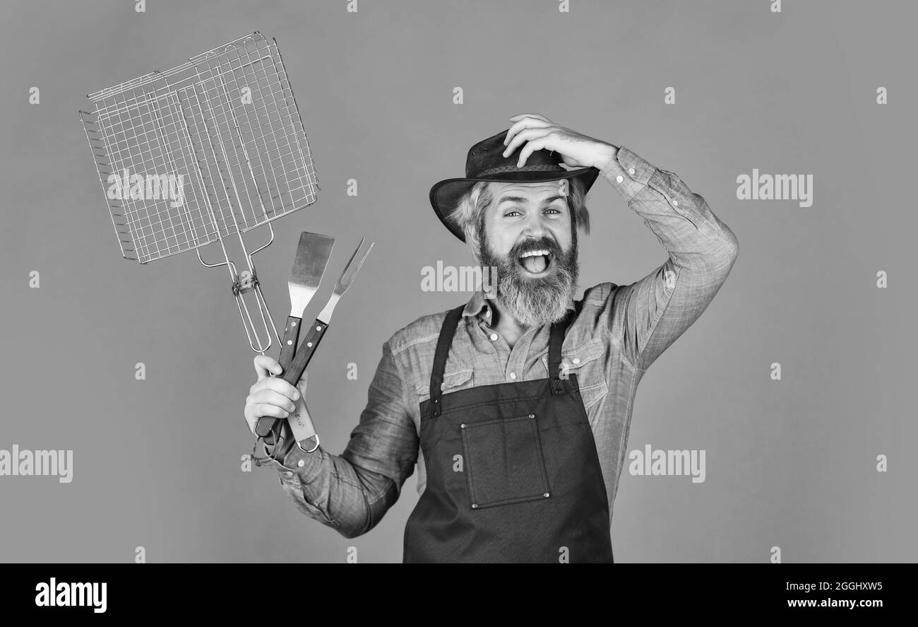 Picnic e barbecue. Bistecca e barbecue. Barbecue. Grigliare gli alimenti. Picnic americano. Tradizione familiare. Cottura carne. Stagione primaverile. Usura allevatore con bearded Foto Stock