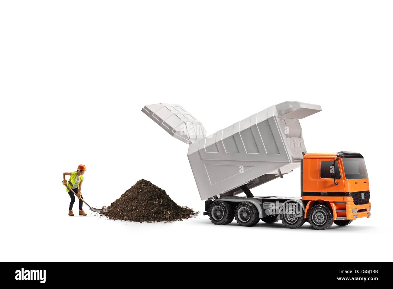 Lavoratore di costruzione che indossa un elmetto e una cintura di attrezzi, scavando con una pala accanto un camion di scarico isolato su sfondo bianco Foto Stock