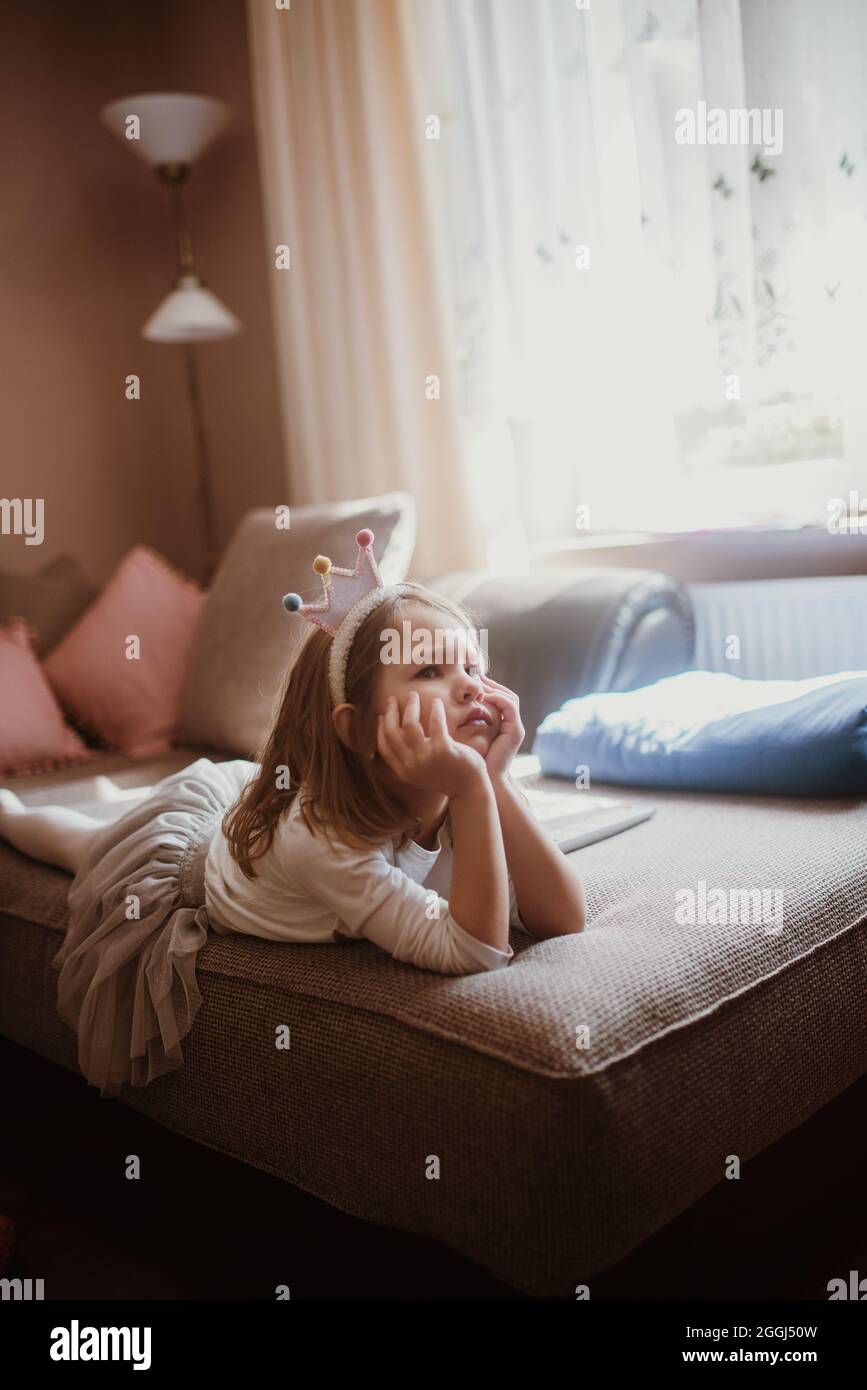 La bambina arrabbiata in costume è sdraiata sul letto. Foto Stock