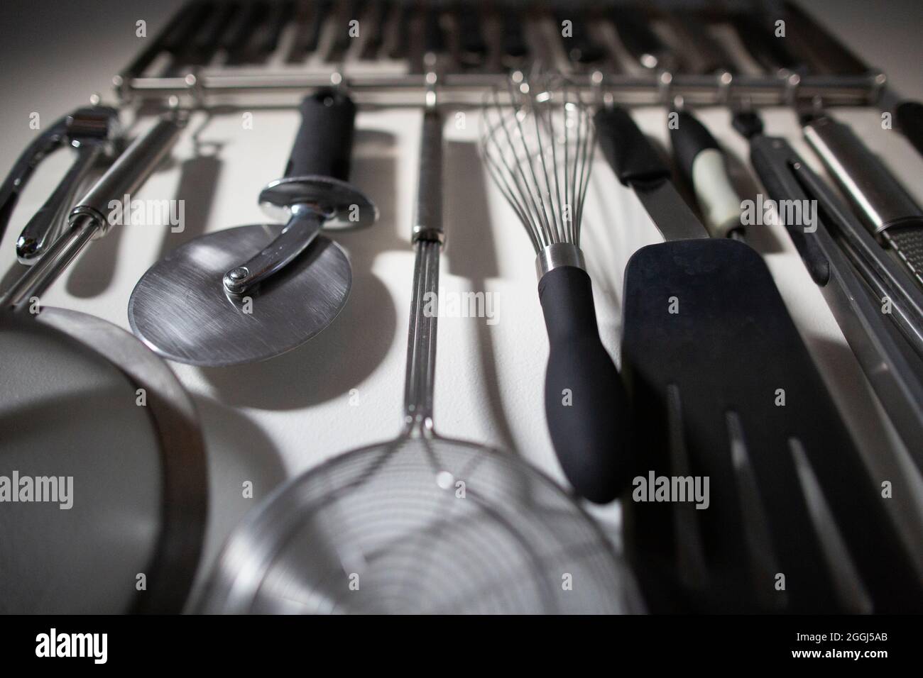 Gruppo di attrezzi della cucina organizzati che appaiano sul muro della cucina domestica Foto Stock