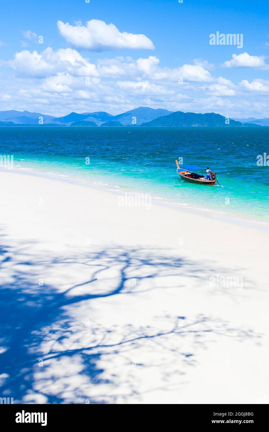 Vista sul mare di pura isola tropicale in estate soleggiata, astratta alberi ombra sulla spiaggia di sabbia bianca, pescatore guida barca da pesca nel mare blu. Foto Stock