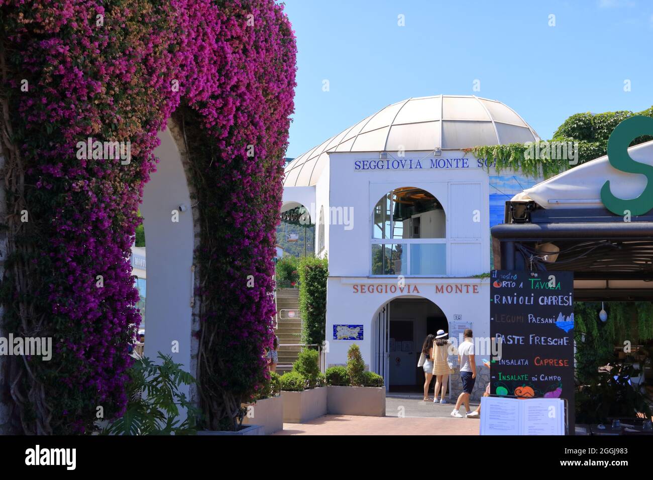 14 2021 luglio - Capri, Italia: Bella stradina della città di Anacapri, città mediterranea con alberi fioriti e case bianche Foto Stock