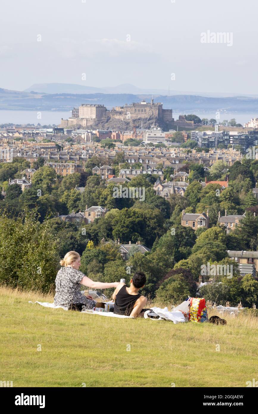 Una coppia che ha un picnic a Blackford Hill, Edimburgo con una vista dello skyline di Edimburgo, Blackford Hill, Edinburgh Scotland UK Foto Stock