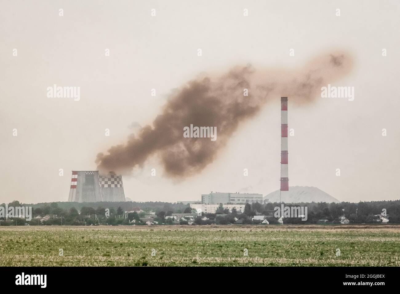 Inquinamento dell'ambiente ed ecologia. Produzione sporca, fumo dalla torre di raffreddamento di un'impresa industriale vicino al camino. Foto Stock