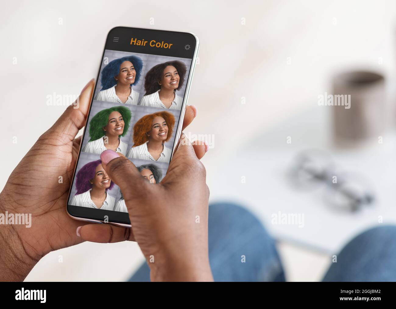 Elegante donna nera che sceglie il colore dei capelli, utilizzando l'app mobile Foto Stock