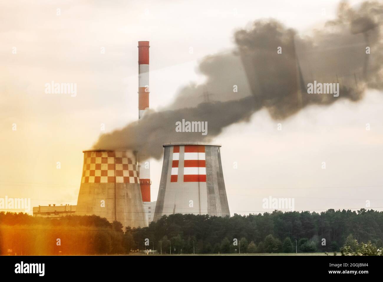 Produzione di sporco. Il fumo grigio viene emesso dalla torre di raffreddamento vicino al camino di un'impresa industriale. Foto Stock