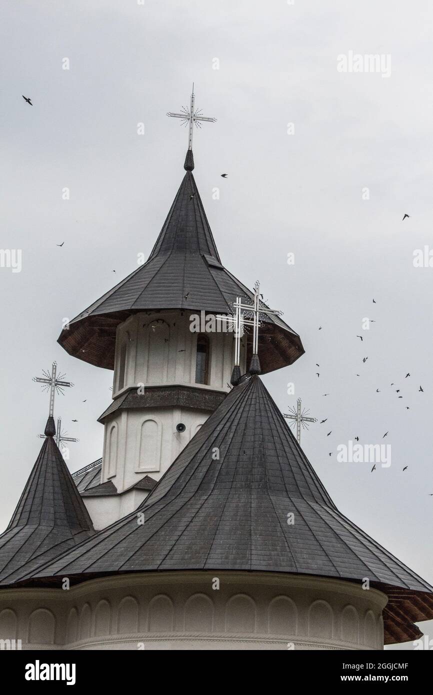 Gregge di uccelli che volano intorno ad una chiesa cristiana ortodossa, in un giorno di moody. Foto Stock
