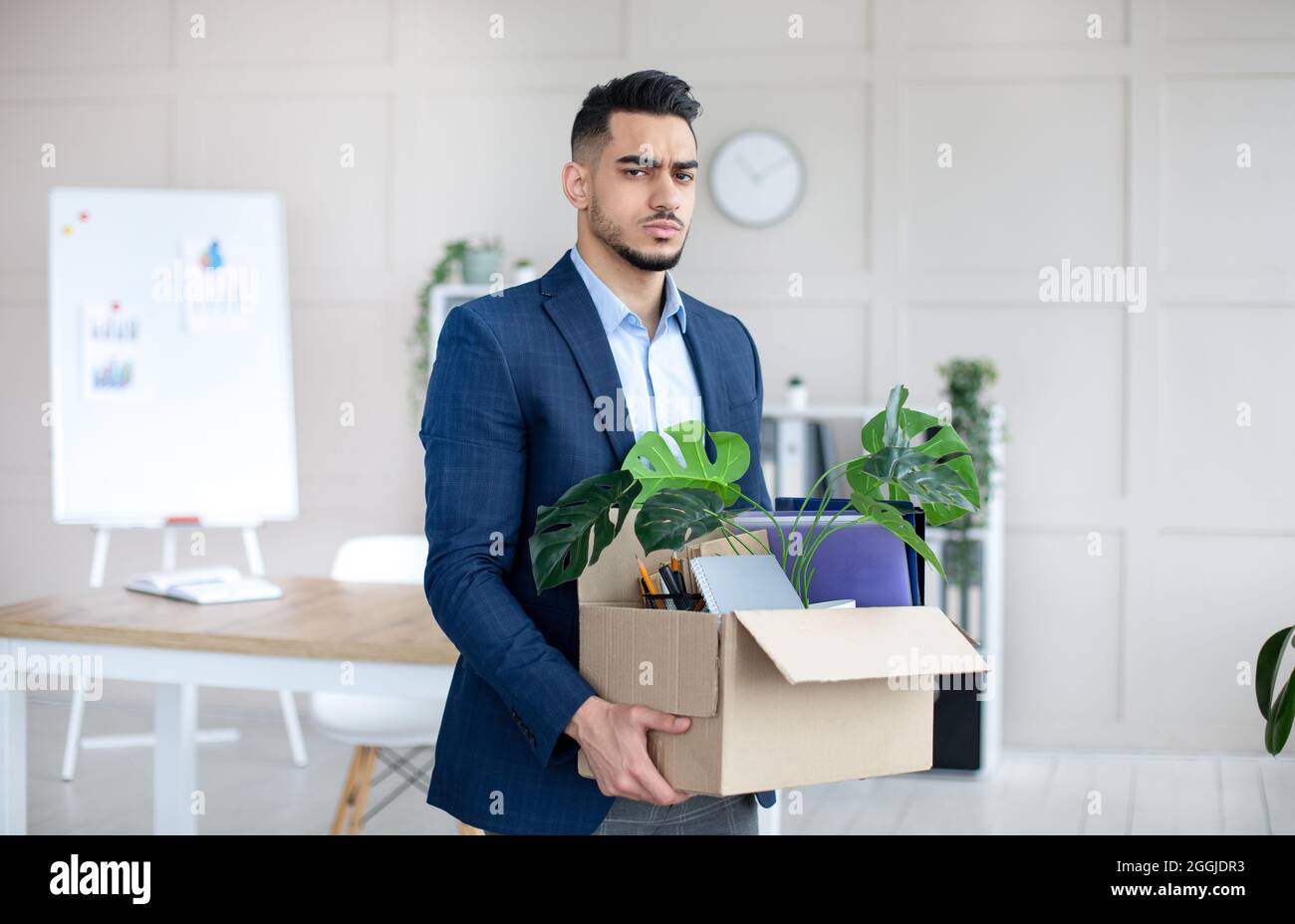 Concetto di crisi economica. Un uomo arabo infelice che detiene effetti personali dopo essere stato licenziato in carica Foto Stock