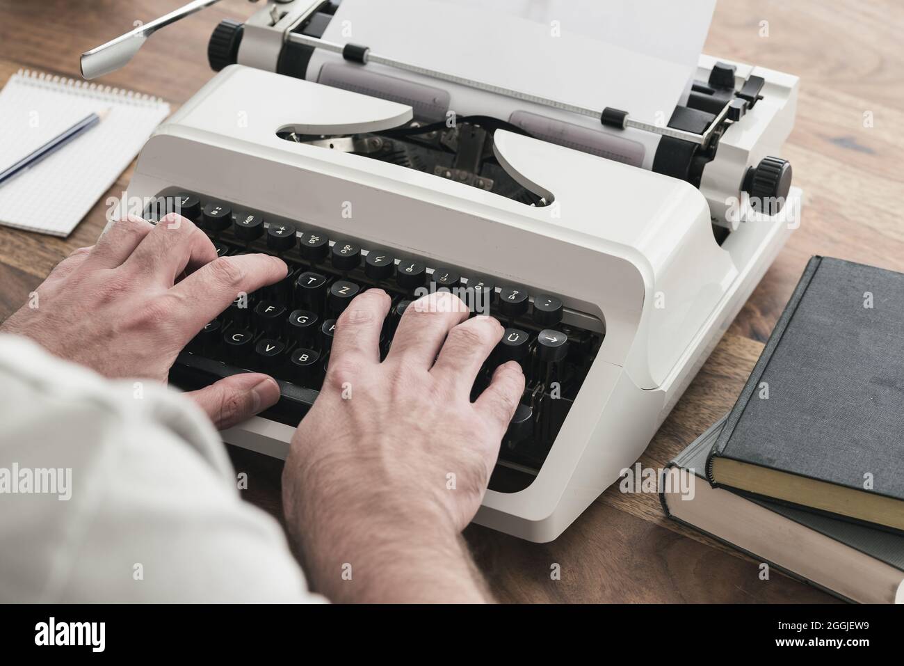 sopra la vista della spalla dell'uomo usando una macchina da scrivere al tavolo di legno Foto Stock