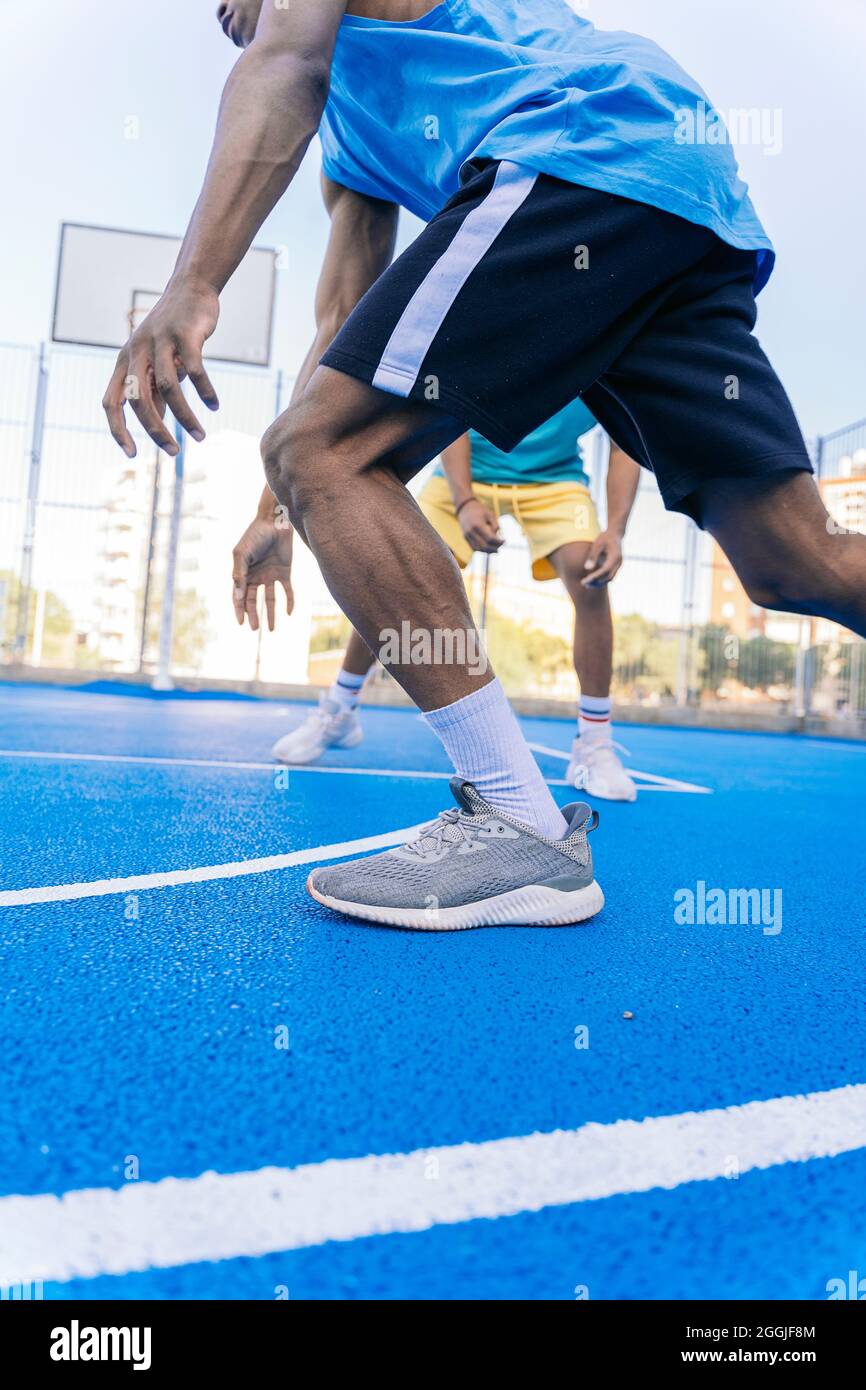 Vista ravvicinata delle gambe di giovani sportivi afroamericani che giocano a Street basket di giorno Foto Stock