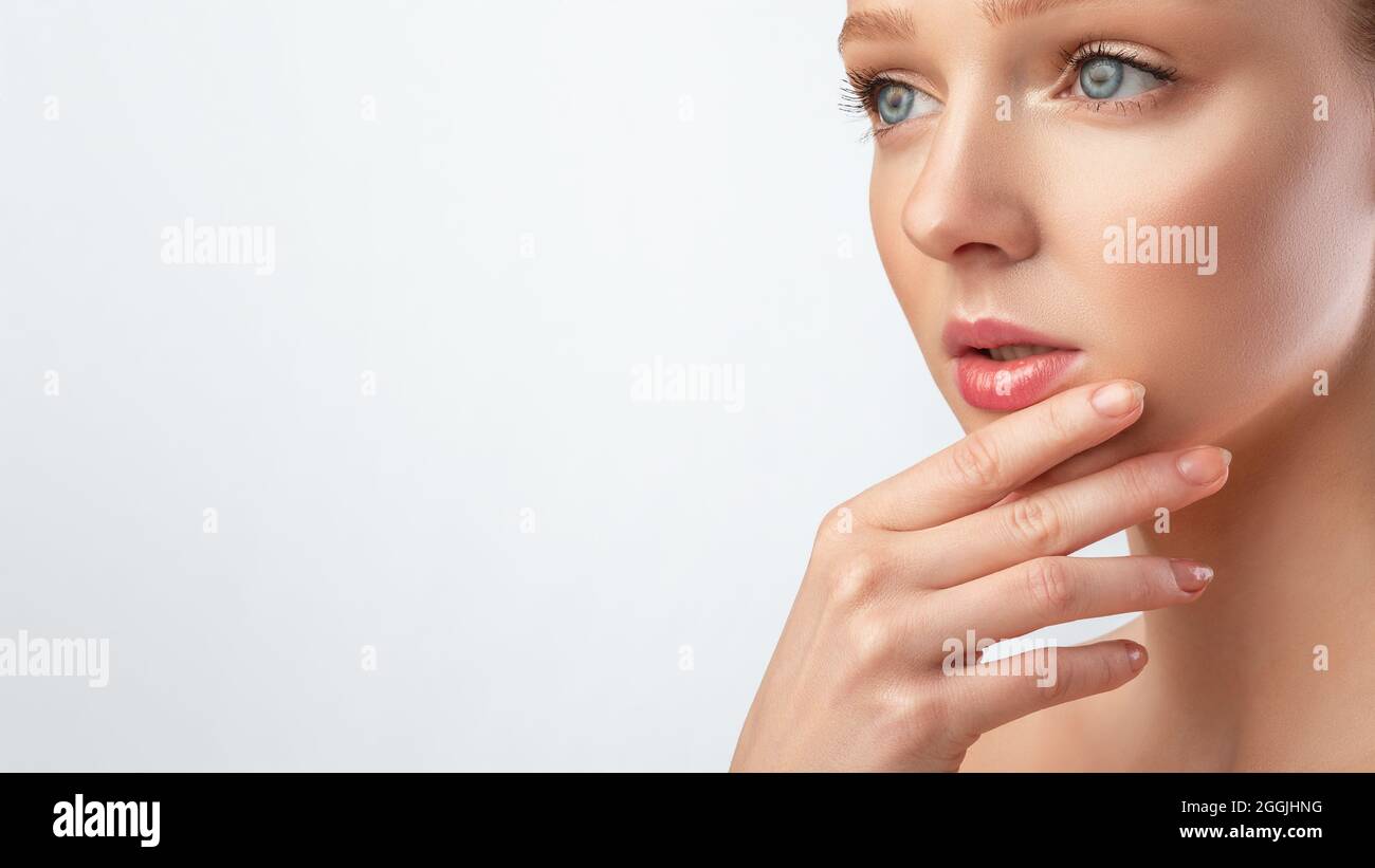 Donna con perfetto Makeup posa toccare Chin, sfondo grigio, ritagliato Foto Stock