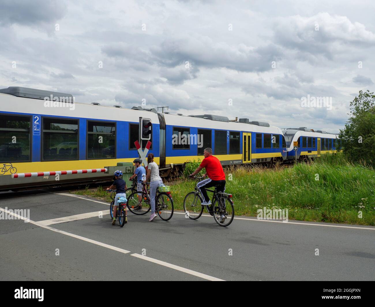 Passaggio a livello vicino Halen, treno regionale, ciclisti, Osnabrücker Land, confine NRW bassa Sassonia, Germania Foto Stock