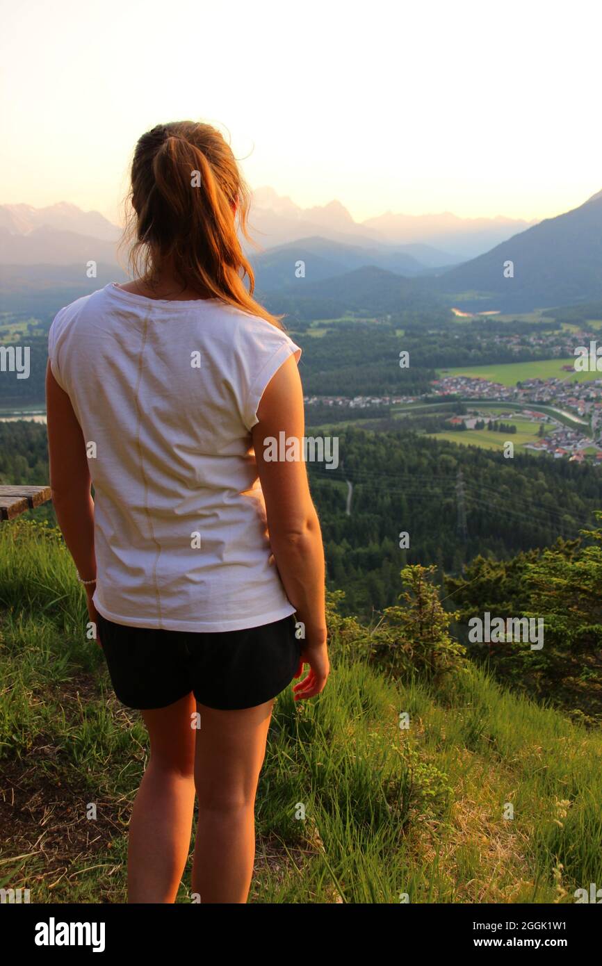 Giovane donna gode della vista durante un'escursione serale in montagna, vista di Krün, Wetterstein montagna, Valle Isar, alta Baviera, Baviera, Germania, Europa Foto Stock
