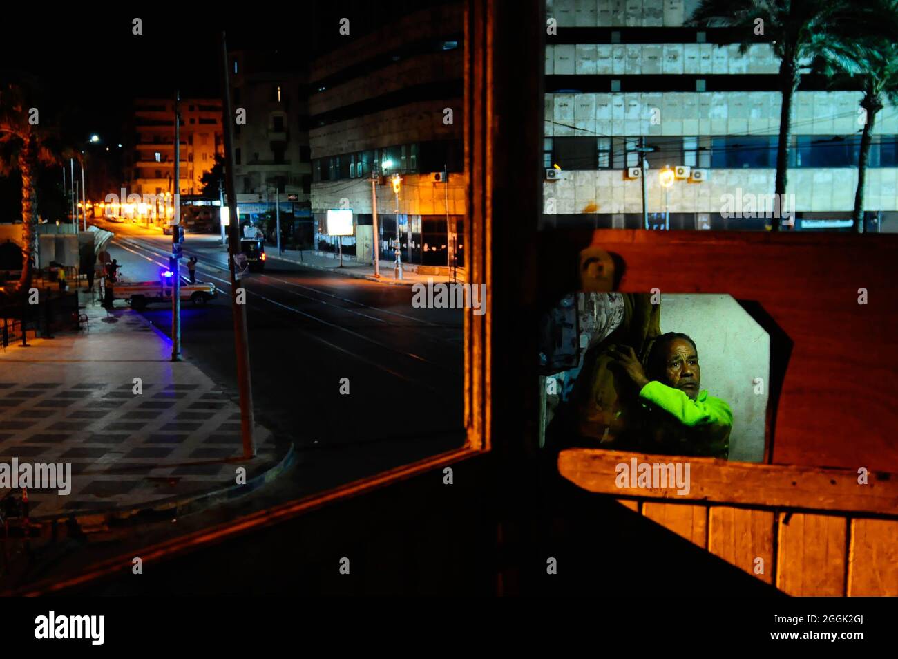 Ezzat, un uomo egiziano senza un rifugio o una casa, rimane in uno stand di polizia nel centro di Alessandria durante il coprifuoco. Alessandria, Egitto. Foto Stock