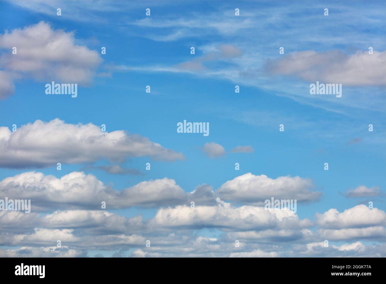 Le nuvole bianche galleggiano in file uniformi attraverso il cielo blu durante il giorno. Spazio di copia. Foto Stock