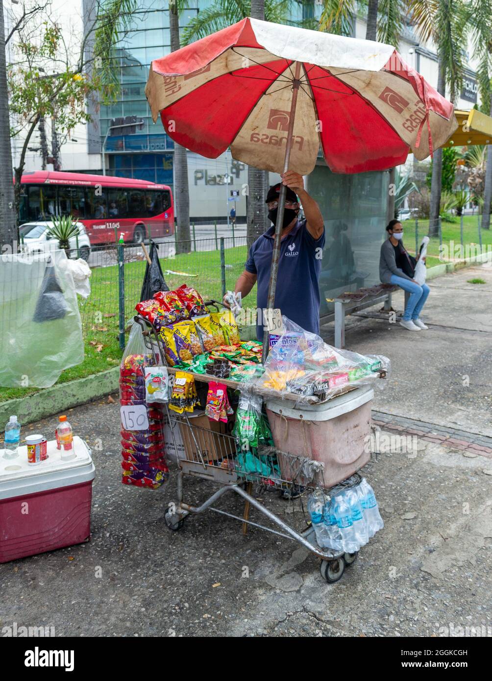Un uomo che vende piccoli oggetti in una fermata di autobus a Nitreoi, Rio de Janeiro, Brasile. Stile di vita di persone reali. Foto Stock
