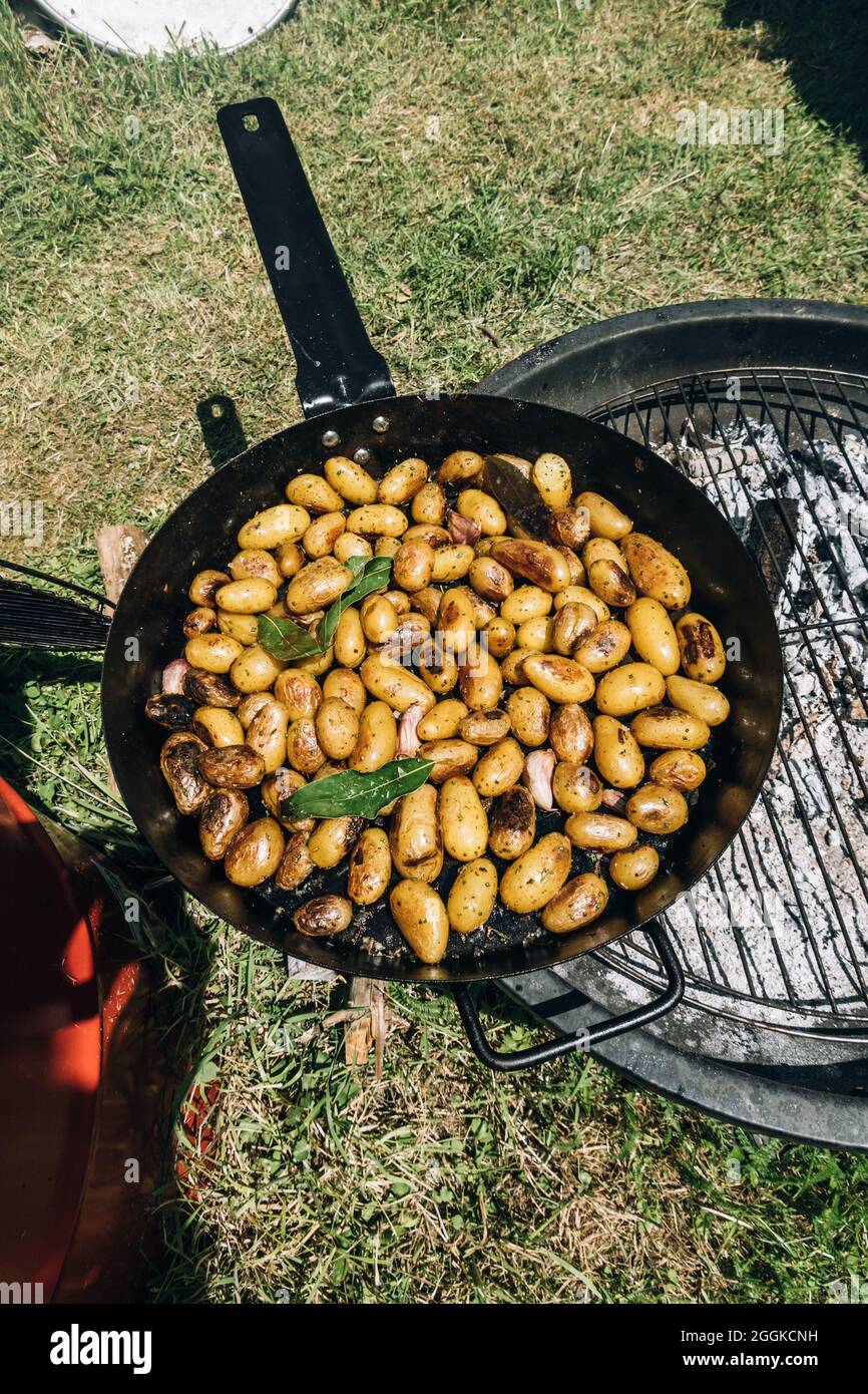 Potatos herbed fritto in una teglia di ferro gigante su una griglia barbecue con alloro alloro alloro, aglio e sale grosso Foto Stock