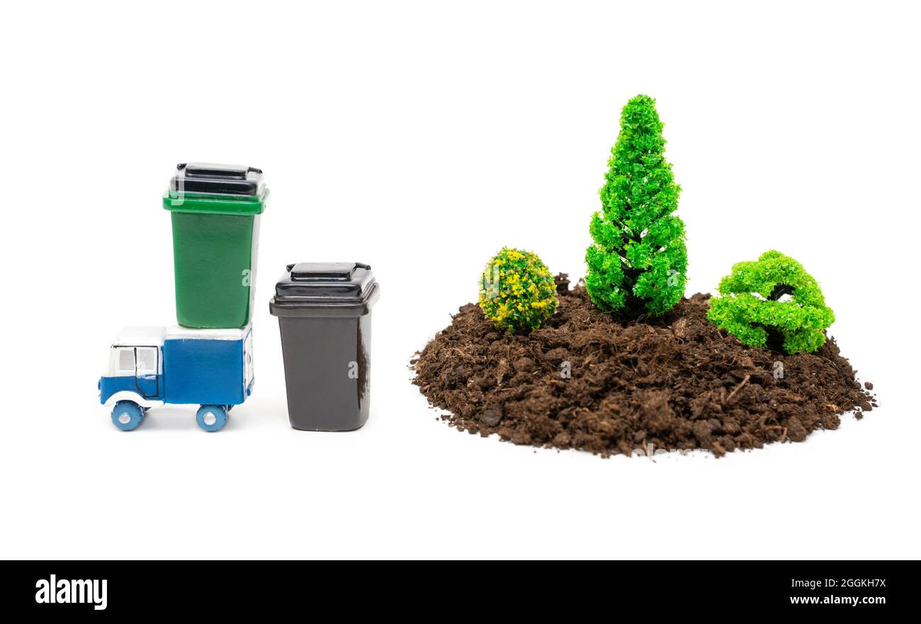 Set-up foresta in miniatura con lattine di rifiuti giocattolo e un camion isolato su bianco Foto Stock