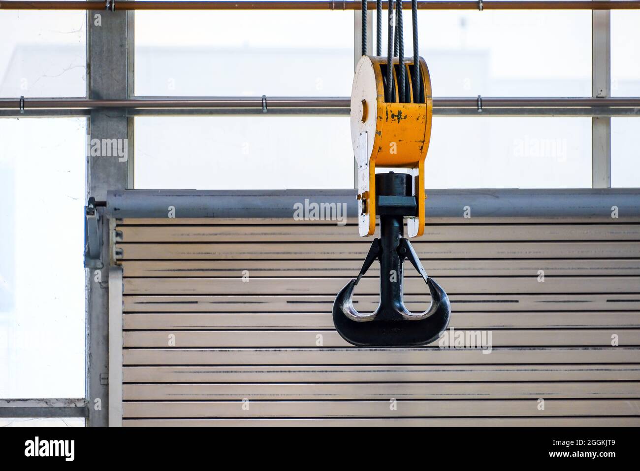 Uebach-Palenberg, Renania Settentrionale-Vestfalia, Germania - Crane si aggancia alla gru a portale di fronte ad una porta a rulli in un locale industriale della fabbrica di macchine NEA. Foto Stock