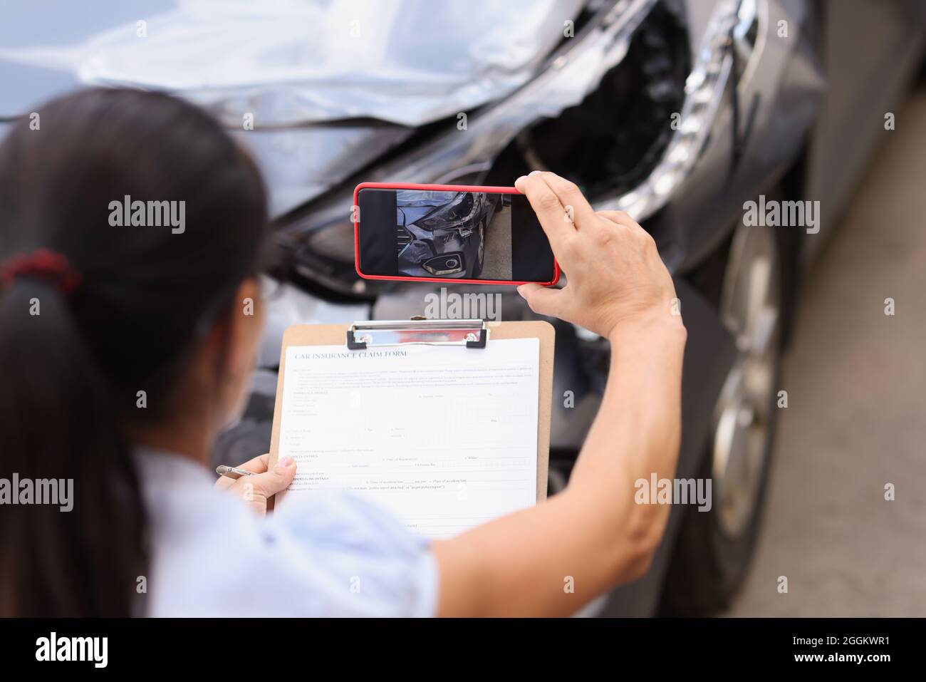 L'agente assicurativo sta riprendendo i danni all'auto che si è schiantata Foto Stock