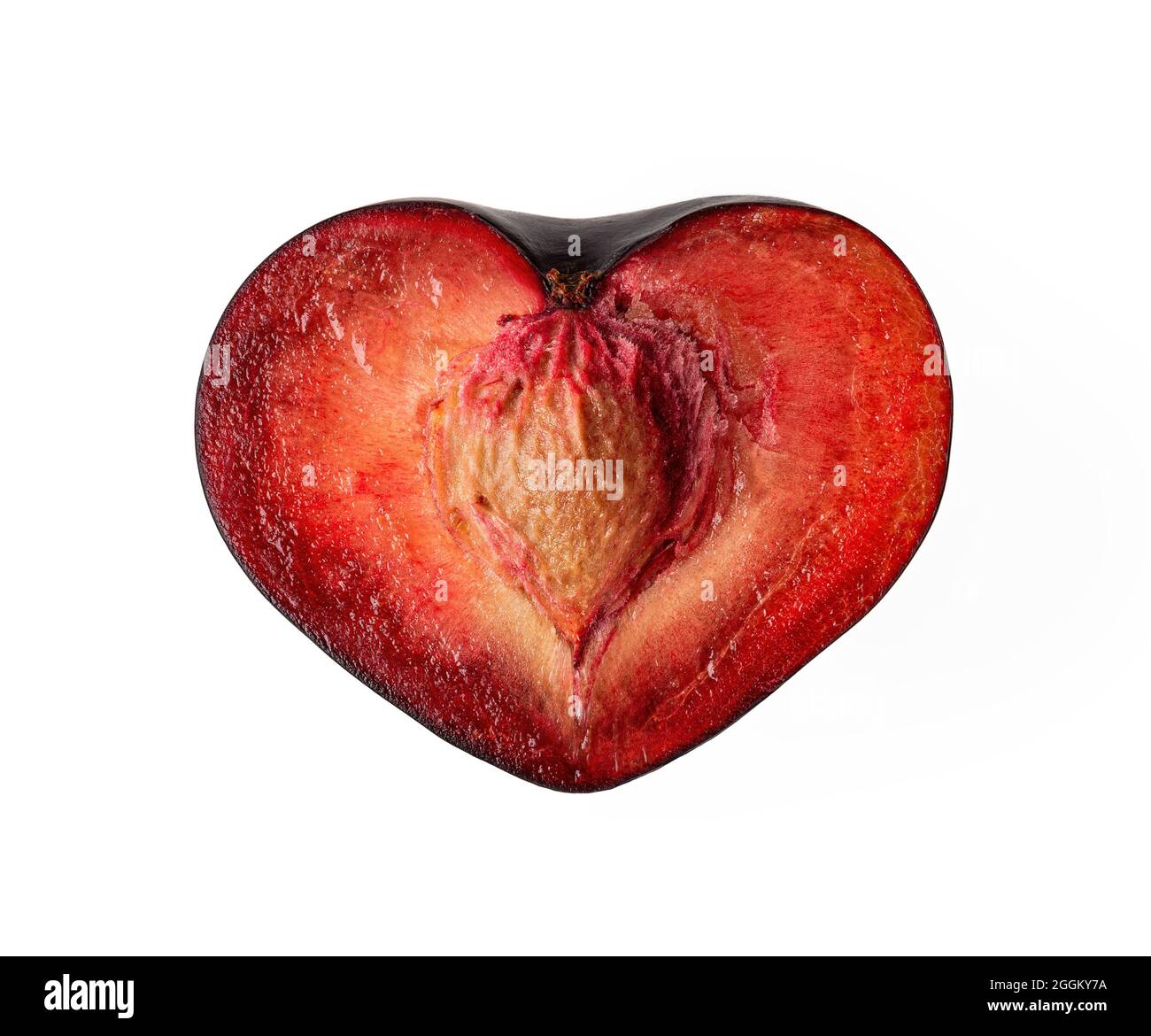 Metà a forma di cuore di susina nera matura succosa con pietra isolata su sfondo bianco. Elemento di design per un'alimentazione sana, uno stile di vita vegano e vegetariano. Foto Stock