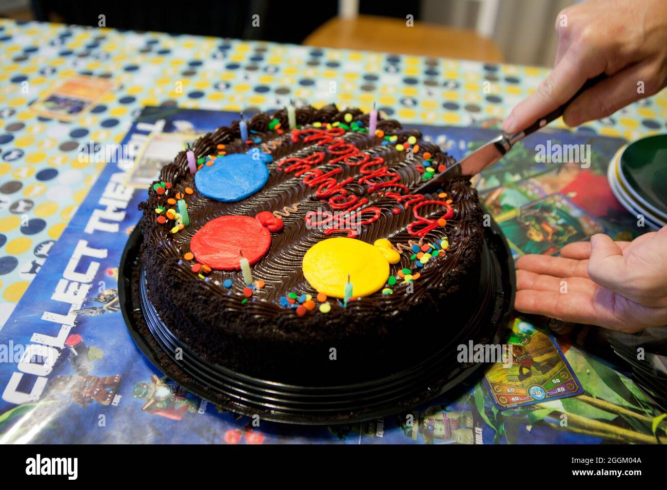 Uomo taglio torta di compleanno cioccolato, primo piano - USA Foto Stock