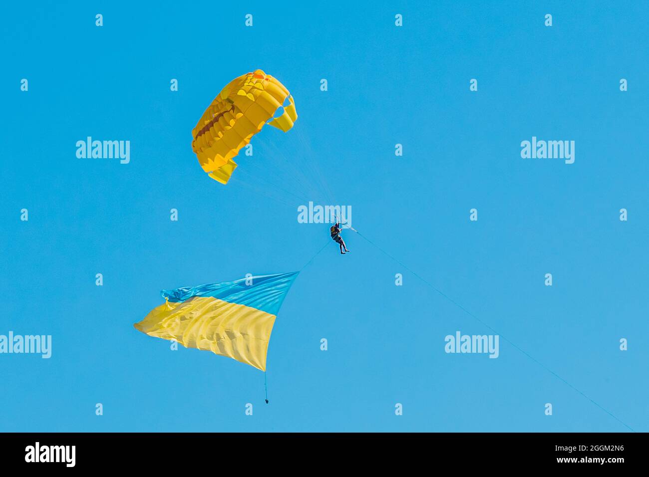 Parashutista nel cielo azzurro chiaro vola con il simbolo nazionale ucraino di sfondo bandiera. Foto Stock