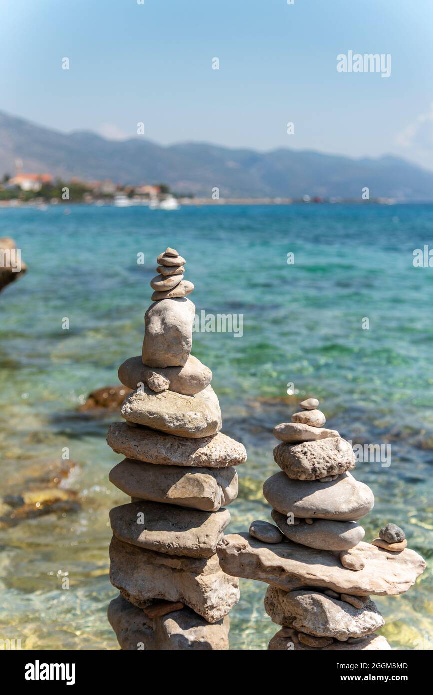 Pietre piramidali equilibrio sulla spiaggia su sfondo blu mare e cielo. Primo piano. Foto Stock