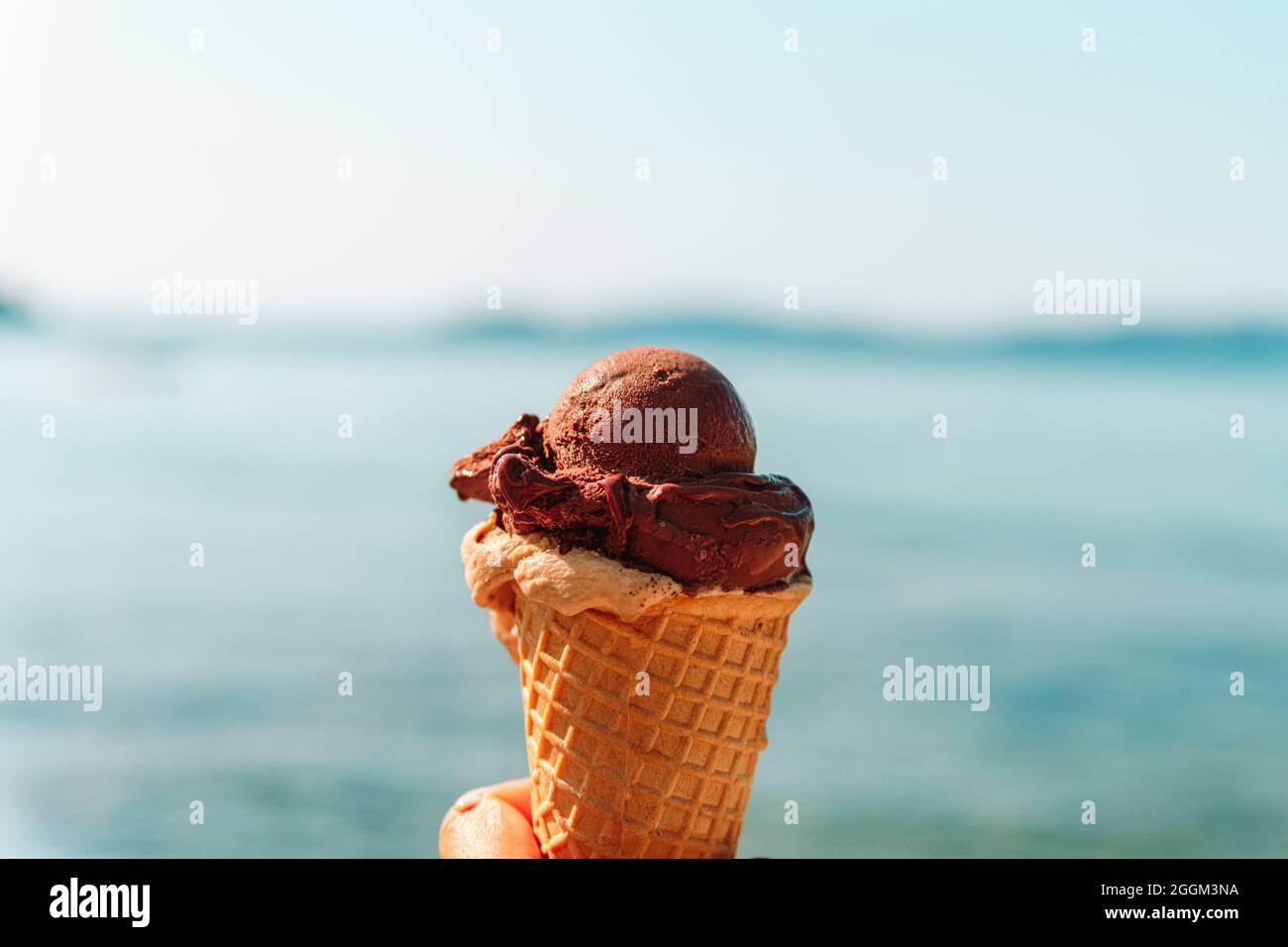 Gustoso gelato a portata di mano sullo sfondo il mare turchese. Foto Stock