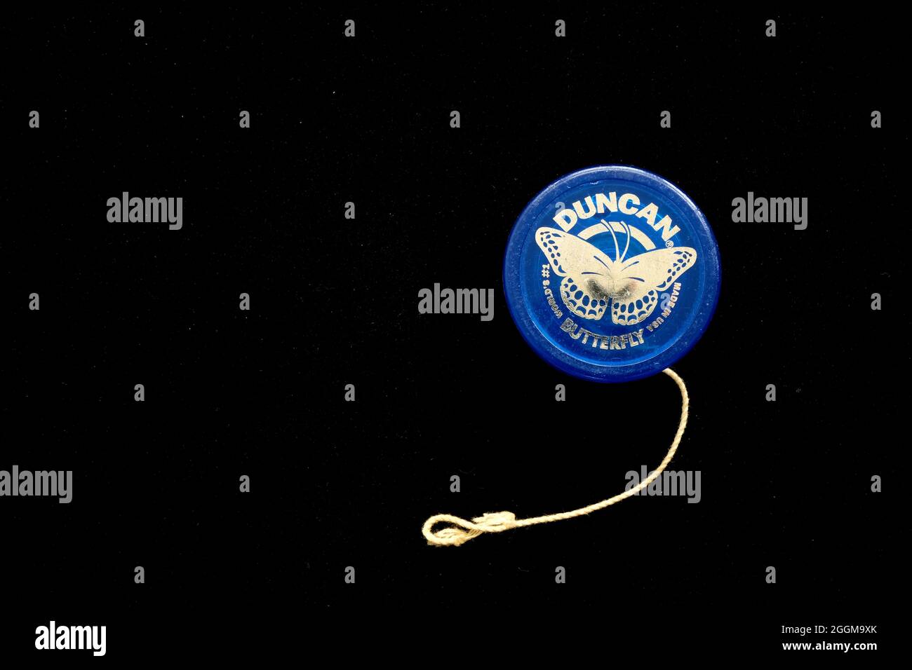 Uno Yo-yo Duncan Butterfly blu per yoing, con stringa e manico che si disgregano su una superficie nera con spazio di copia. Foto Stock