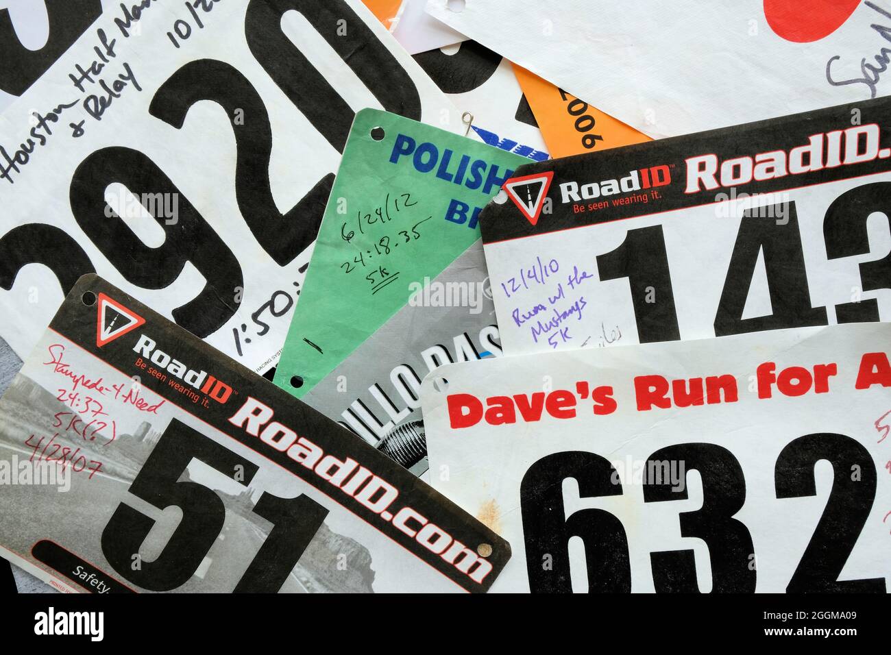 Bib assortiti e casuali da 5k e 10k corse divertenti e gare su strada competitive con risultati manoscritti, tempi e date; bib running. Foto Stock