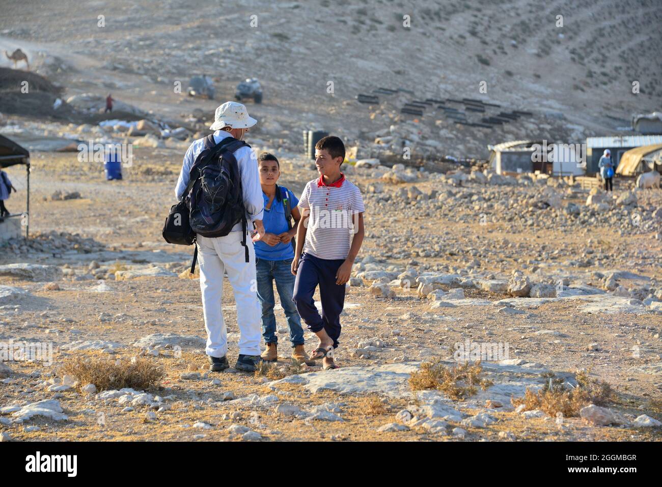 Dal 2004 i bambini del villaggio di Tuba stanno andando a scuola nel vicino villaggio di AT-Tuwani, 2.6 km di distanza - mentre sono stati condotti da un attivista ebraico e un veicolo delle forze di difesa israeliane per proteggerli dagli attacchi violenti da parte dei coloni ebrei religiosi dall'avamposto illegale di Maon Farm, che si trova sul loro cammino verso la scuola. Palestina / Israele, a sud di Hebron. 31 agosto 2021. (Foto di Matan Golan/Alamy Live News) Foto Stock