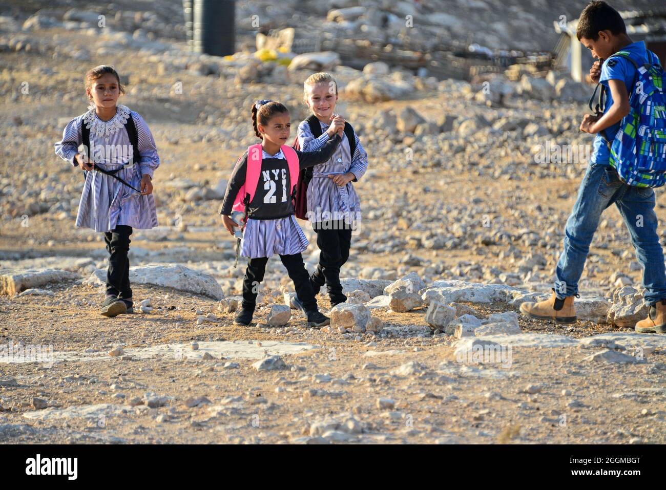 Dal 2004 i bambini del villaggio di Tuba stanno andando a scuola nel vicino villaggio di AT-Tuwani, 2.6 km di distanza - mentre sono stati condotti da un attivista ebraico e un veicolo delle forze di difesa israeliane per proteggerli dagli attacchi violenti da parte dei coloni ebrei religiosi dall'avamposto illegale di Maon Farm, che si trova sul loro cammino verso la scuola. Palestina / Israele, a sud di Hebron. 31 agosto 2021. (Foto di Matan Golan/Alamy Live News) Foto Stock