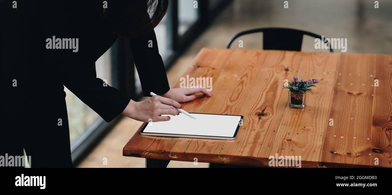 Primo piano di una donna d'affari che lavora da scrivania disegnando su un tablet bianco con schermo vuoto Foto Stock