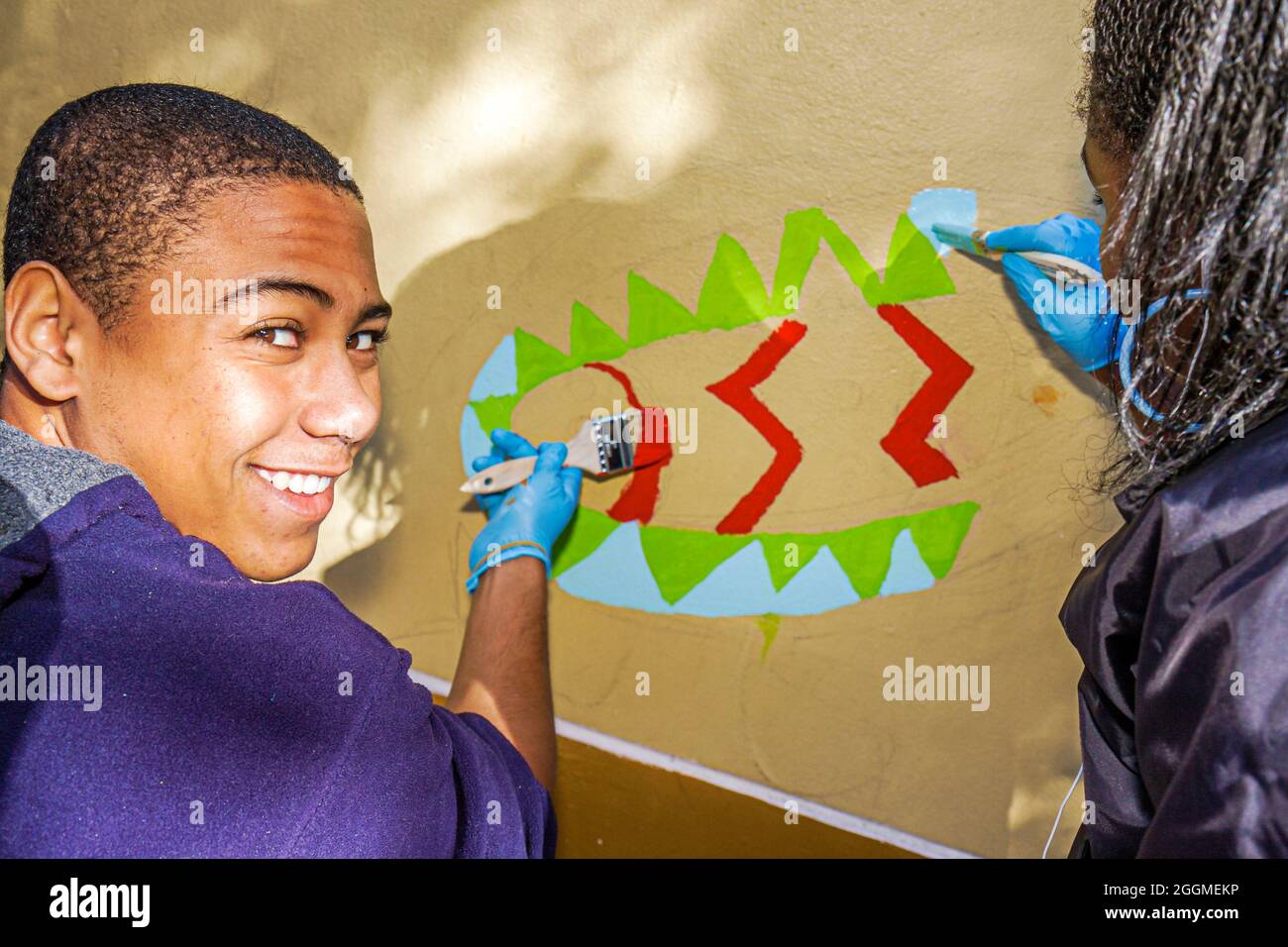 Miami Florida,volontariato volontario che lavora aiutando,Martin Luther King Jr. Giorno di servizio,MLK studente Black boy teen teenager murale pittura sorridente Foto Stock