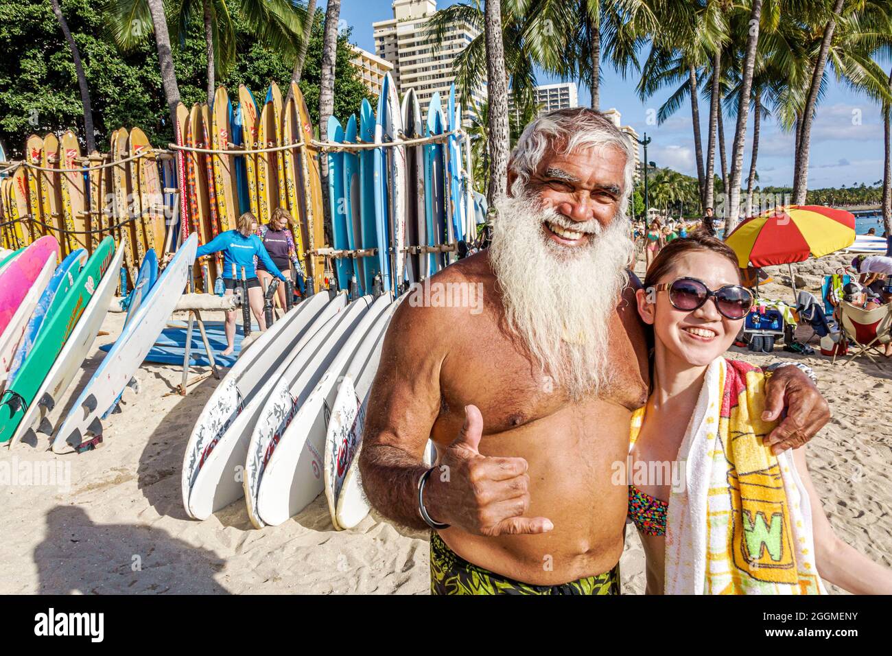 Honolulu Hawaii,Oahu,Hawaiian,Waikiki Beach,Kuhio Beach state Park,uomo maschio lungo bianco barba surfer,donna asiatica donna donna affitto shaka segno appendere sciolto ha Foto Stock