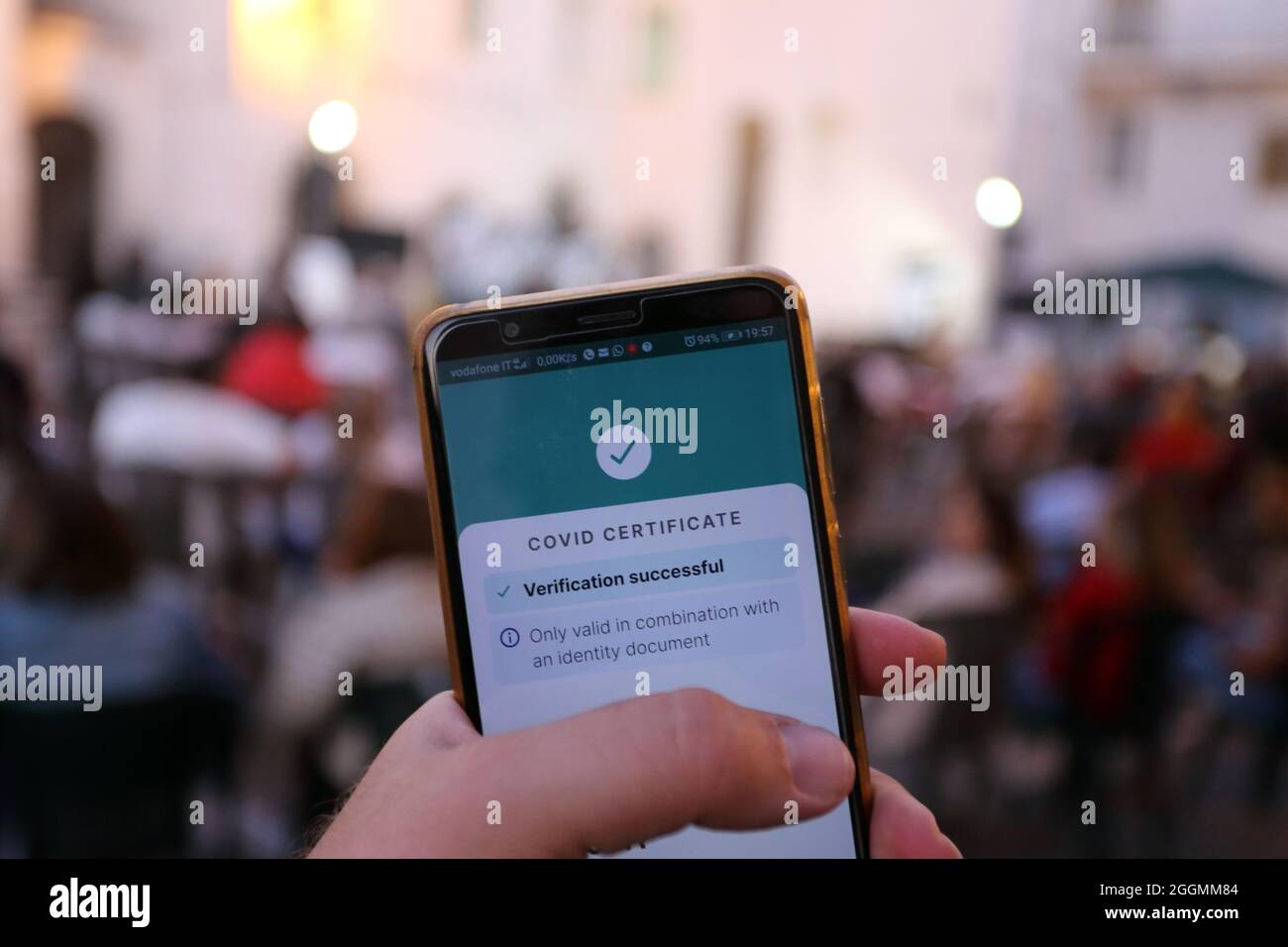 Convalida del certificato Covid riuscita: Primo piano dello smartphone e folla sfocata dietro Foto Stock