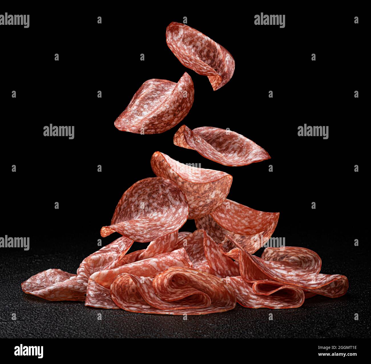 Fette di salame cadenti isolate su sfondo nero Foto Stock